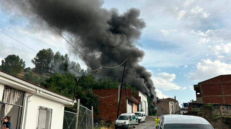 <i>Bomberos sofocan las llamas en la nave agrícola de Campillo de Arenas tras el incendio.</i>