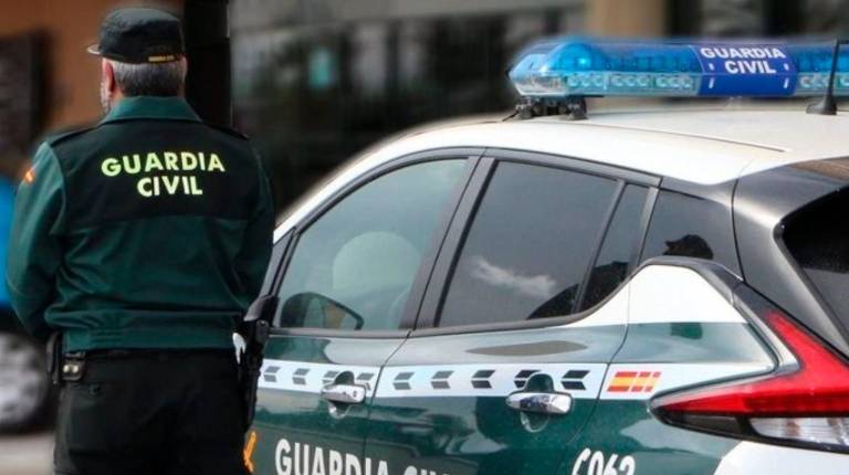 <i>Un agente de la Guardia Civil, de espaldas, junto a un vehículo oficial. Archivo. / Guardia Civil.</i>