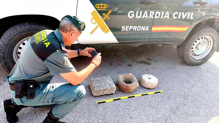 <i>Un agente de la Guardia Civil fotografía los tres objetos. / Guardia Civil.</i>