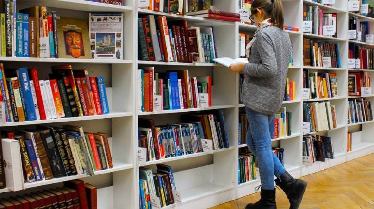 <i>Una mujer ojeando libros en una biblioteca. / Junta de Andalucía. </i>