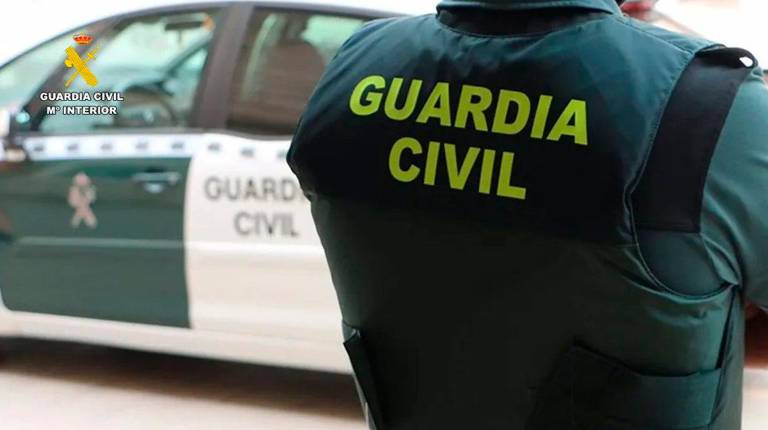 <i>Un agente de la Guardia Civil junto a un vehículo oficial. Archivo. / Guardia Civil.</i>