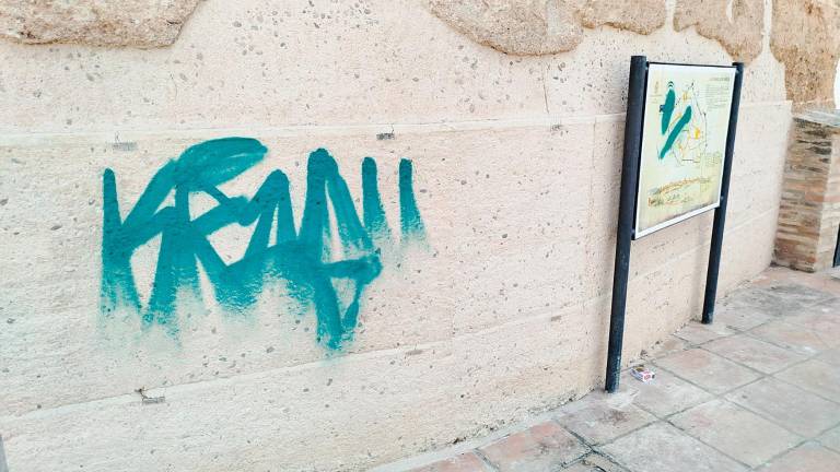 Pintadas sobre la muralla y un panel explicativo del monumento.