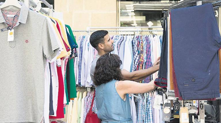 COMERCIO<i>. Foto de archivo donde dos usuarios comprueban la oferta de una tienda de ropa.</i>