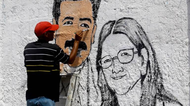 <i>Miembros de la organización “Fortín 4F” pintan grafitis en favor de Nicolás Maduro y su esposa, Cilia Flores, en las calles de Puerto Cabello. / Europa Press.</i>