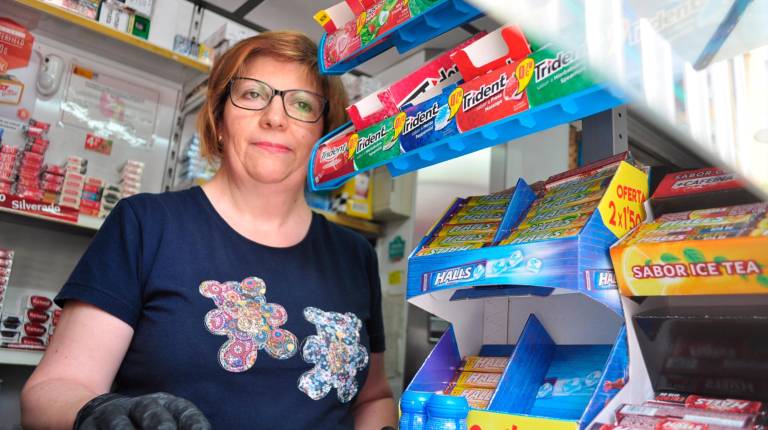 ATENCIÓN. <i> Carmen Pérez atienda a un cliente tras la mampara del estanco número 13 de Roldán y Marín.</i>