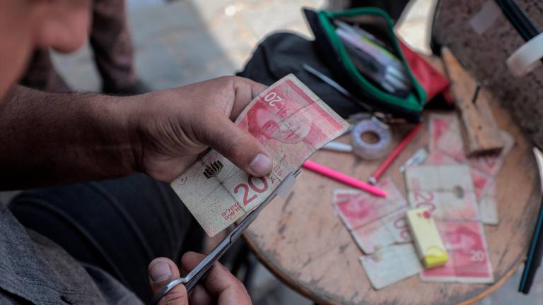 Un palestino arregla un billete desgastado, en el sur de la Franja de Gaza. / Rizek Abdeljawad / Europa Press.