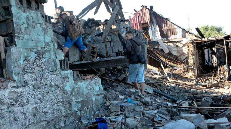 <i>Personas entre los escombros tras un bombardeo. </i>