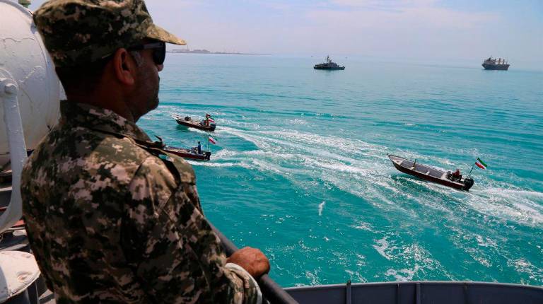 <i>Un miembro de la Guardia Revolucionaria Islámica observa varias lanchas iraníes de la milicia paramilitar Basij a su paso por el Golfo Pérsico / Archivo / Europa Press</i>