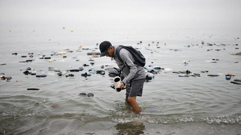 <i>Un hombre recoge unas chanclas del agua. / Jesús Torres / Europa Press. </i>