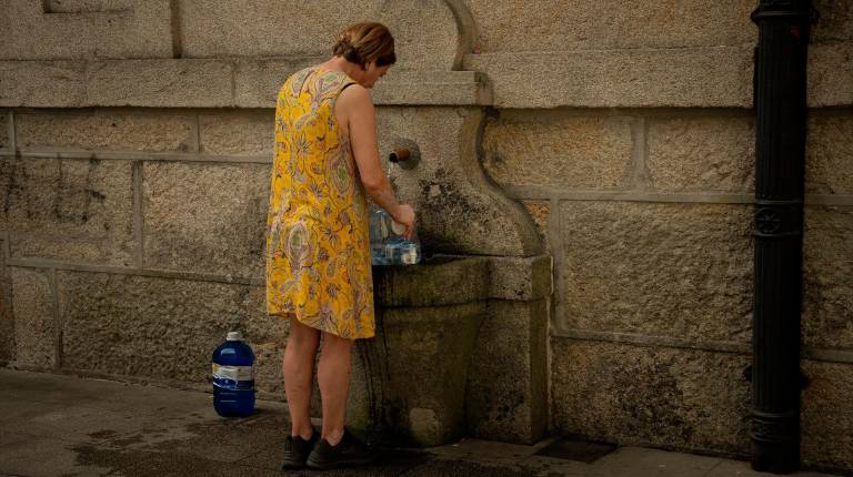 <i>Una persona rellena botellas de agua en una fuente pública. / Europa Press. </i>