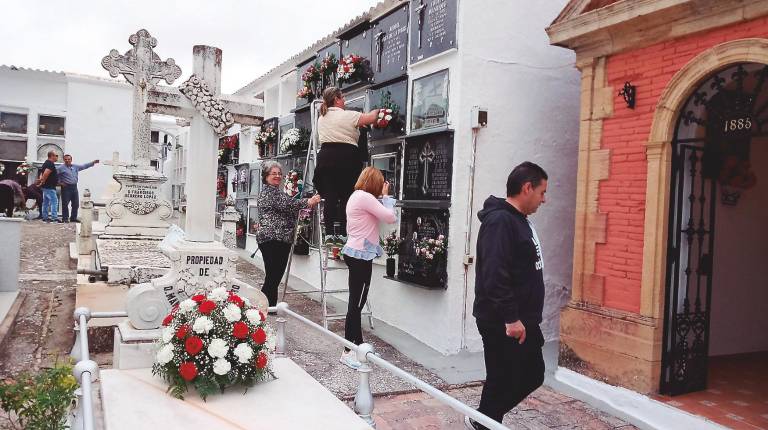MOMENTOS.<i> Arriba, unas mujeres colocan flores en Lopera. A la izquierda, familiares decoran las tumbas de sus seres queridos en Torres y, a la izquierda, velas encendidas en Villanueva del Arzobispo.</i>