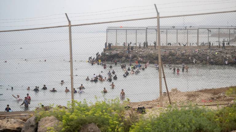 <i>Decenas de personas intentando cruzar la frontera por el espigón del Tarajal, en Ceuta, en imagen de archivo. / Marcos Moreno / Europa Press.</i>