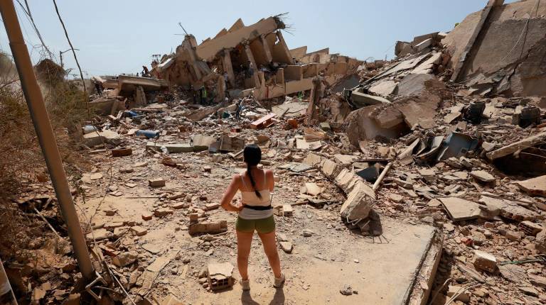 <i>Una mujer frente a varias casas derruidas por los terremotos. / Javier Campos / DPA.</i>