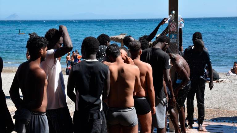 <i>Varias personas se asean en las duchas públicas, en la playa del Trampolín. / Europa Press. </i>