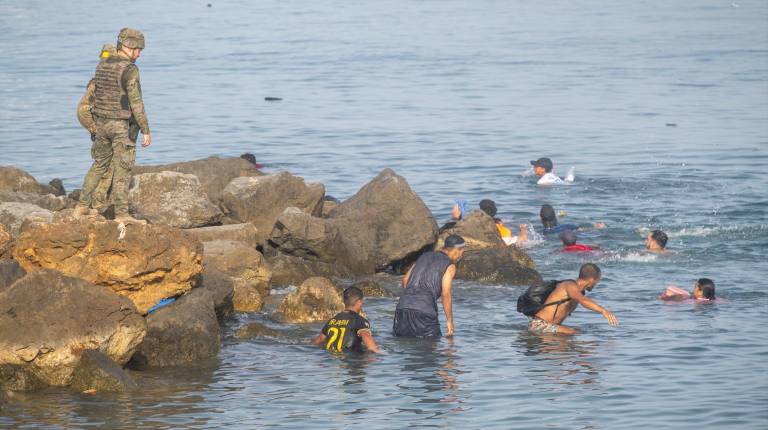 <i>Decenas de migrantes intentan cruzar a España desde Marruecos por el espigón fronterizo en Ceuta.</i>