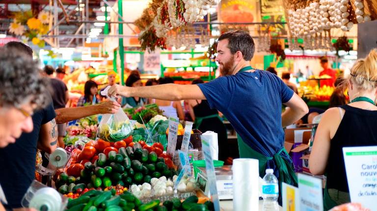 <i>Imagen de archivo de un vendedor atendiendo a un grupo de personas en un mercado. / Junta de Andalucía. </i>