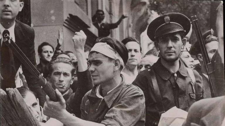 <i>Un civil armado junto a un guardia de asalto en las inmediaciones del Cuartel de la Montaña de Madrid tras la sublevación militar del 18 de julio. / Biblioteca Nacional de España. </i>
