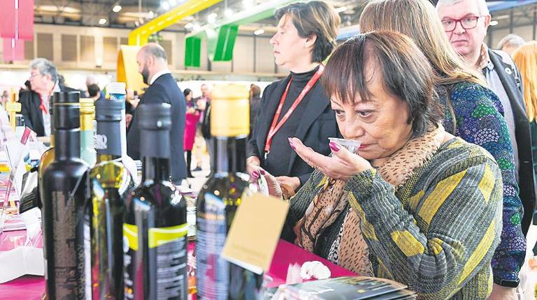 <i>Una visitante huele el aroma de un Aove jiennense en la feria. / Agustín Muñoz / Diario JAÉN.</i>
