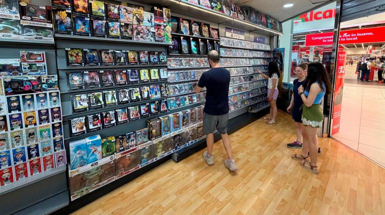 <i>Consumidores de videojuegos en formato físico echan un vistazo en la estantería de PlayStation en el Game Shop de Linares. / Francisco J. Marín / Diario JAÉN</i>