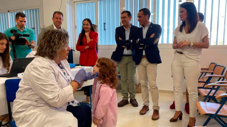 <i>Una profesional sanitaria administra la vacuna antigripal intranasal a una alumna en el CEIP Ángel López Salazar de Baeza, bajo la mirada de los delegados de Sanidad, Lucía Mónica Pérez Nava, y de Educación, Francisco José Solano. / Junta de Andalucía. </i>