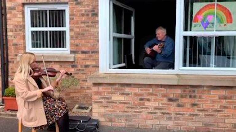 Esta mujer toca el violín para sorprender a su abuelo, de 72 años, en aislamiento por la crisis del coronavirus