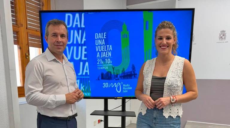 <i>Julio Millán y Beatriz López posan delante del cartel de la Media Maratón de Jaén, que cumple su trigésima edición. / Ayuntamiento de Jaén. </i>