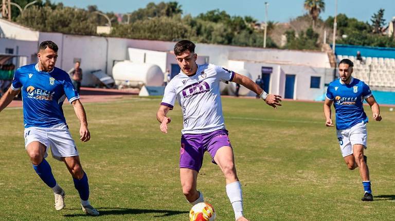 <i>El ya exjugador del Real Jaén David Serrano controla el balón entre dos jugadores de la UD Melilla. / Miranda López / Real Jaén CF. </i>