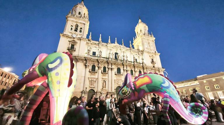 <i>Dos lagartos coloridos pasean con la Catedral de fondo en una Plaza de Santa María a rebosar de personas durante los primeros compases de la cabalgata inaugural de la Feria de San Lucas 2026. / Fotografías: F. Gaitán / Diario JAÉN.</i>