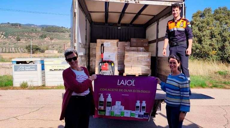 <i>Un voluntario de Protección Civil de Beas de Segura carga uno de los palets; Laura y Olga González sostienen un cartel de Laiol.</i>
