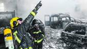 DESTROZOS. Un bombero señala el tejado de una de las naves, en la que había varios vehículos totalmente calcinados. (Agustín Muñoz) 