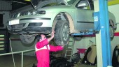 REVISIÓN. Un hombre revisa los bajos de un vehículo en el interior de un taller de coches.