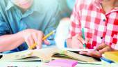 EDUCACIÓN. Dos personas estudian con interés las páginas de un libro y subrayan las partes más importantes para el aprendizaje.