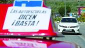 PRÁCTICAS. Dos coches de autoescuela durante unas clases, con carteles en contra de los paros. 