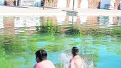 2015. Dos jóvenes se bañan en la playa artificial de Mogón.