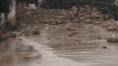 SUSTO. Acumulación de piedras y fango en la calle; personal y maquinaria municipal en las tareas de limpieza.