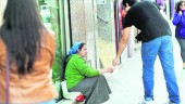 MENDICIDAD. Un joven da una moneda a una mujer de nacionalidad rumana, en la Avenida de Andalucía.