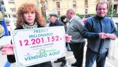 FELIZ. María de los Ángeles García Donoso —mujer del encargado del punto de venta, Miguel Ángel Hurtado— sostiene el cartel con el dinero repartido.