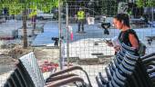 PLAZA. Una joven pasa junto a las sillas apiladas de una terraza, mientras los operarios trabajan en la zona. 